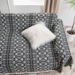 Thick black and white geometric jacquard sofa cover with fringe in cozy home setting
