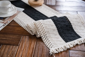 Close-up of black and cream woven table runner with crochet lace and boho tassels