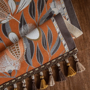 Floral jacquard table runner with orange and grey botanical patterns and silk tassels