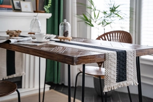 Close-up of black and white woven table runner with intricate knit texture and long tassels