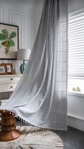 Detailed view of light blue farmhouse curtain with white grid patterns and fringe trim