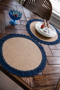 Detail van ronde placemat van natuurlijk jute met marineblauwe kant op de tafel