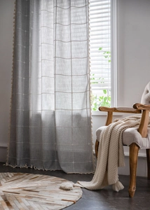 Detail view of gray plaid curtains with textured fabric and handmade fringe tassels