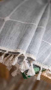 Detailed macro view of grey checkered fabric curtains with decorative beige tassels