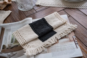 Close-up of woven table runner with black and white color blocks and handmade fringe