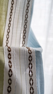 Detailed macro view of striped embroidery fabric with diamond patterns on linen curtain