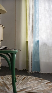 Détail de rideaux à rayures verticales avec broderie chaîne marron et bordure à pompons