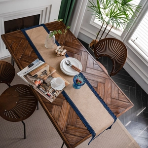 Natuurlijke jute tafelloper met marineblauwe kanten rand op houten eettafel