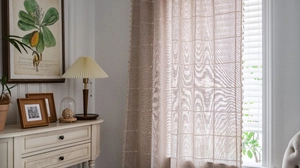 Detail of beige plaid embroidered curtain with tassel fringe in farmhouse style decor