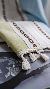 Detail of green and white striped curtain with brown chain embroidery and tassel trim