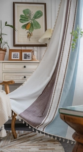Détail de rideau en coton lin rayé avec pompons crème et design vertical bicolore