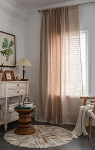 Close-up of linen striped curtains with decorative fringe in a rustic interior setting