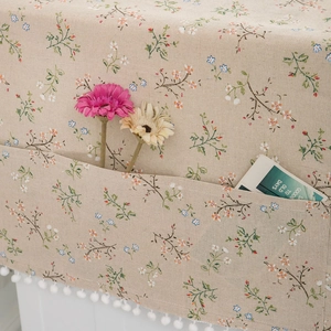 Detailed view of floral dust cover with side storage pocket and white pom-pom fringe