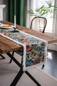 Detail of floral jacquard table runner featuring colorful woven flowers and fringe trim