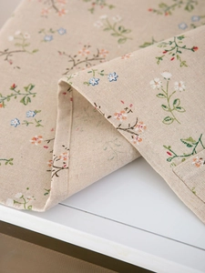 Close-up of pastoral linen fabric with small floral patterns and neat stitched edges