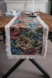 Detailed macro view of American style floral jacquard fabric table runner with beige tassels
