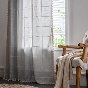Grey lattice pattern curtain with cream tassels in a cozy farmhouse style interior
