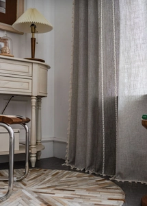 Detail of linen curtain fabric with white pom-pom trim and vertical geometric stitching