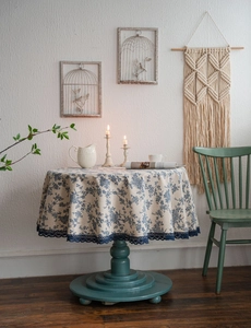 Detailed view of blue floral print tablecloth with elegant lace edge on round cotton linen