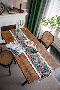 Close-up of American vintage floral jacquard table runner with white fringe on a wood table