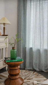 Détail du rideau en lin bleu clair avec rayures brodées blanches et pompons à franges