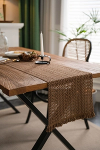 Macro shot of dark brown hand-woven hollow knit table runner with boho tassel details