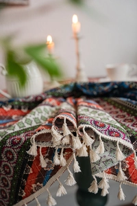 Detail of bohemian ethnic tablecloth featuring mandala prints and elegant beige fringe