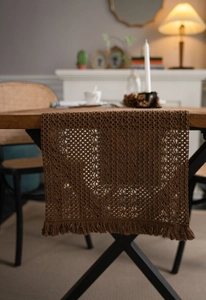 Close-up of khaki woven table runner with dense tassels and geometric patterns