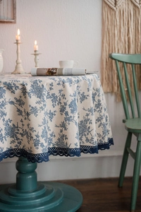 Detail of round cotton linen tablecloth with vintage blue floral pattern and lace edge