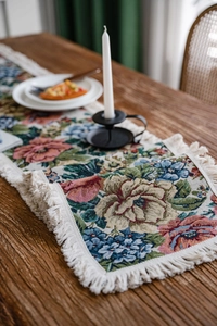Close-up of vintage floral jacquard table runner with decorative white tassels