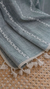 Detail of light green cotton linen curtain with white leaf embroidery and tassel trim