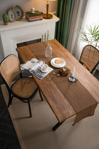 Top view of khaki woven table runner on dark wood dining table in cozy room