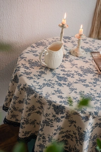 Close-up of blue floral print tablecloth with dark blue lace edge on cotton linen fabric