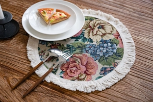 Close-up of vintage floral tapestry table runner with fringe on a rustic wooden desk