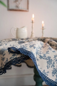 Detailed shot of retro blue floral linen tablecloth with elegant wide hollow lace borders