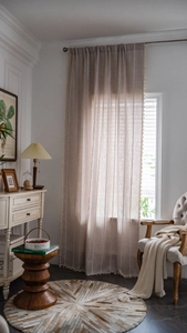 Gros plan de rideaux en lin beige avec broderies verticales et bordures à glands