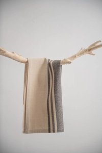 Close-up of linen napkin with brown stripes hanging on natural wood branch
