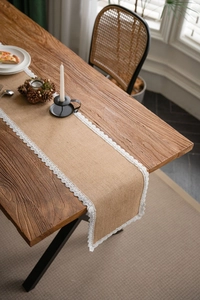 Detailed close-up of natural jute table runner featuring delicate white lace embroidery edges
