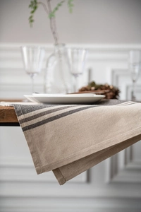 Close-up of linen table runner with grey stripes on a rustic wooden dining table