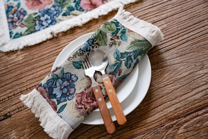Close-up of floral jacquard table runner with decorative ivory white tassels