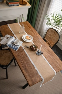 Detailed view of natural jute table runner with delicate white lace edge on wood table