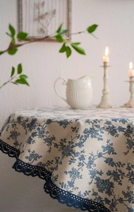 Close-up of blue floral print linen tablecloth with detailed dark blue lace border