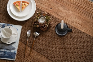 Detailed close-up of dark brown hollow-out knitted table runner on rustic wood table