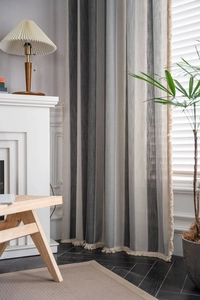 Detailed view of striped woven curtain with fringed edges in a cozy living room setup