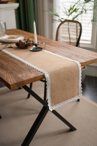 Detail of natural burlap table runner with elegant white lace embroidery for table decor