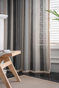 Detailed texture of vertical striped curtain with decorative fringe in a cozy room