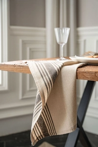 Detail of vintage coffee striped linen napkin draped over a rustic wooden table edge