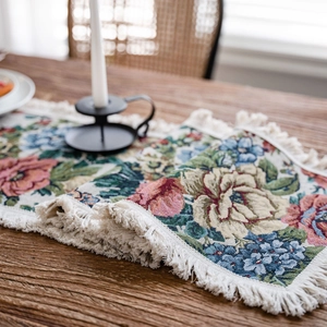 Floral jacquard table runner with white fringe on a rustic wooden dining table