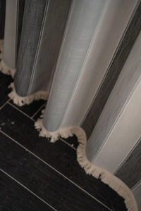 Detailed view of striped curtain fabric texture with elegant off-white tassel fringe trim