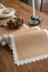 Detail of rustic natural burlap table runner with elegant white lace trim and floral texture